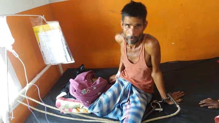 Detainee Ratan Biswas with handcuff in hospital bed photo.